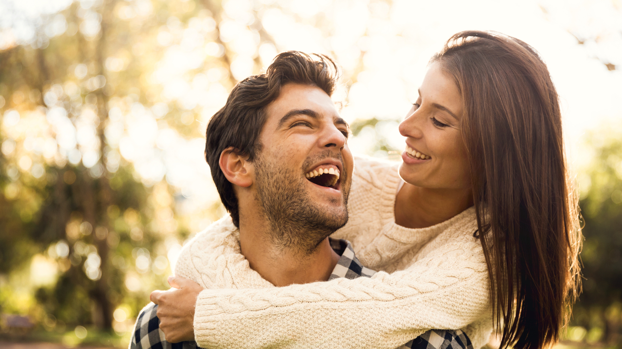 A happy couple laughing together outdoors in warm sunlight